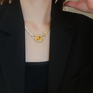Close-up of vintage gold necklace featuring a yellow oval gemstone and crystal halo