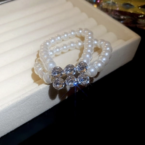 Macro detail of double-row pearl bracelet with a sparkling crystal flower center