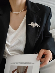 Silver heart and arrow brooch pinned on a black suit lapel for a minimalist styled look
