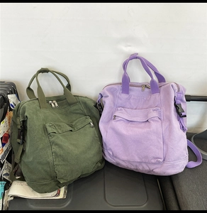 Detail of army green and lilac canvas backpacks with metal zippers and buckles