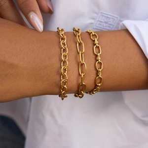 Close-up of three 18k gold plated stainless steel chain bracelets worn on a wrist