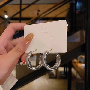 Detail view of silver C-shaped chunky hoop earrings on jewelry card with 925 silver post