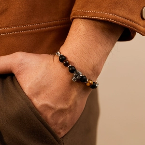 Close-up of tiger eye and matte black beaded bracelet with silver wolf head charm