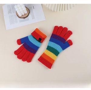Detail of colorful rainbow striped knitted gloves with decorative cuff logo on warm background