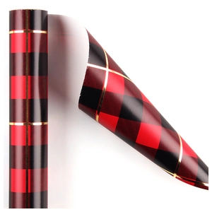 Red and black buffalo plaid gift wrapping paper with elegant gold lines in a roll