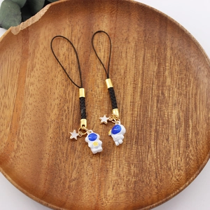 Cute astronaut phone charm pendant detail shot featuring black braided rope and golden star.