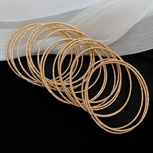 Macro shot of 20pcs textured gold bangle set with fine faceted details on black background