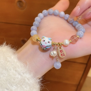 Detail of beaded bracelet with lavender beads, lucky cat ceramic and golden tag