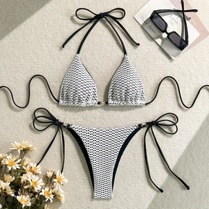 Detailed flat lay of white crochet knit bikini with black ties and gold metal ring hardware