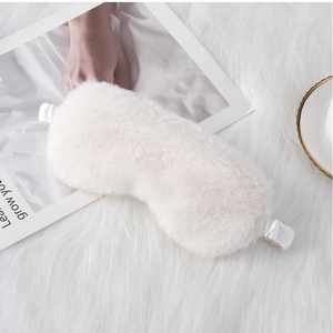 Detail of soft cream plush eye mask with elastic silk strap on white faux fur background