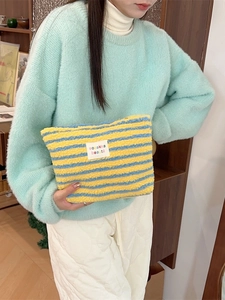 Winter plush striped makeup bag in yellow and blue colors held by a model