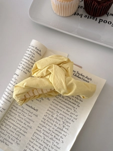Detail of light yellow pleated fabric hair claw clip on magazine with cupcakes backdrop