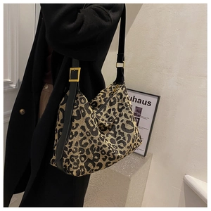 Detail of leopard print tote featuring textured fabric and adjustable gold metal buckle