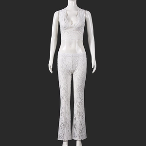 Detailed view of white lace fabric texture on slim-fit crop top and flared trousers set