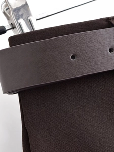 Detail of dark brown double-breasted suit fabric with textured leather belt and metal buckle