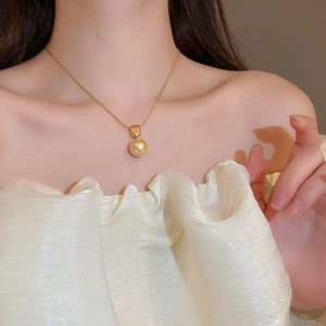Détail d'un pendentif perle champagne sur une fine chaîne torsadée plaquée or 18 carats
