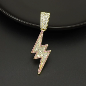 Macro shot of gold lightning bolt pendant with pink and clear crystals on black plate