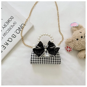 Detail of girls houndstooth handbag with pearl handle and black lace bow decoration