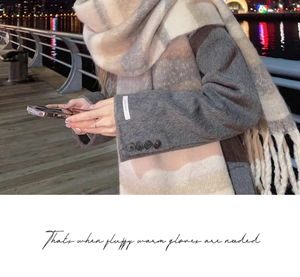 Close-up of beige and gray plaid scarf with thick fringe detail worn with a gray coat