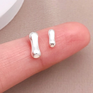 Primo piano di piccole perle metalliche argentate a forma di osso per riferimento taglia