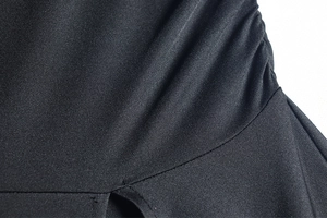Détail du tissu élastique noir avec texture froncée et coutures précises sur la robe