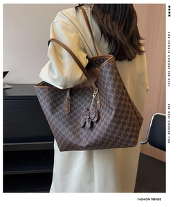 Detailed view of women's tote bag with brown letter monogram pattern and flower charm