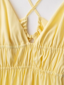 Détail d'une robe d'été jaune avec décolleté en V, lien à nouer et finitions plissées