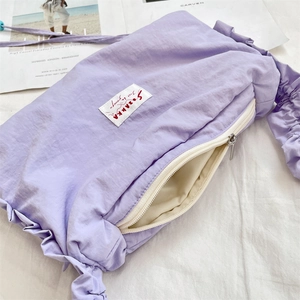 Close-up of purple pleated shoulder bag with brand patch and detailed nylon texture