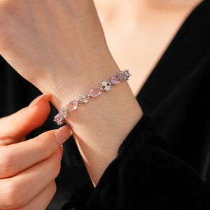 Detailed shot of pink zircon gems and silver clover charms on a vintage style bracelet