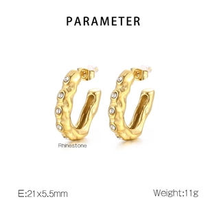 Detail view of gold U-shaped earrings with hammered texture and vertical rhinestone inlay