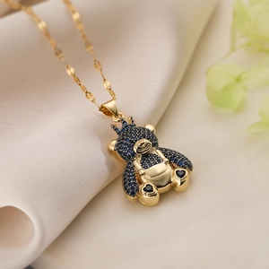 Golden bear pendant necklace with crown and navy blue crystal on soft silk background