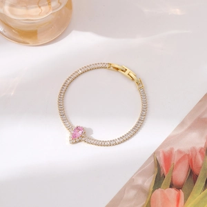 Detail of gold bracelet with sparkling pink pear-cut gemstone and rectangular zircons