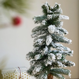 Mini wooden desktop Christmas tree with white flocking snow on a beige background