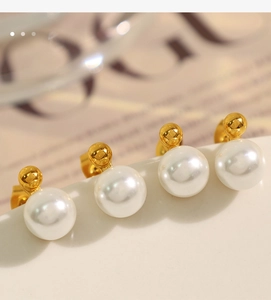 Macro shot of elegant round white pearl earrings with gold bases on a curved stand
