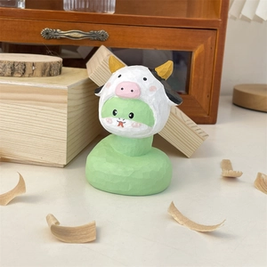 Figurine de serpent en bois sculpté avec chapeau de vache sur bureau rustique