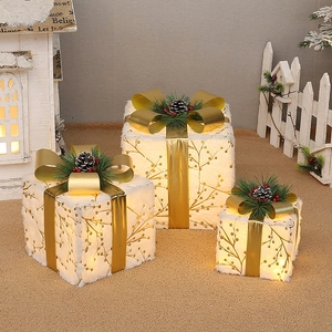 Detail of white plush Christmas gift box with gold ribbon and warm LED lights