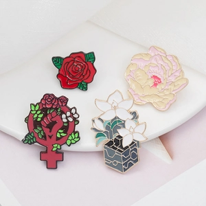 Close-up of four floral enamel pins featuring roses and female symbol on white plate