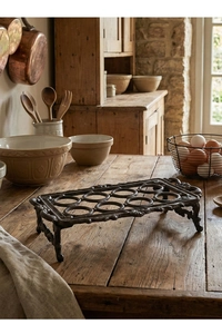 Detail van een 12-vaks gietijzeren eierhouder met vintage snijwerk op een houten tafel