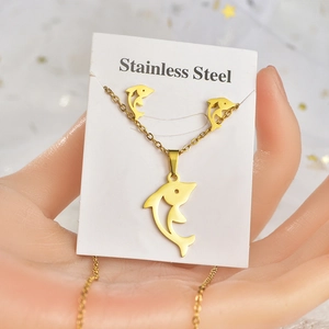 Detailed view of dolphin pendant necklace and earrings set in golden stainless steel