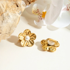 Détail de clips d'oreilles fleur dorés 18K avec perles et texture de métal martelé