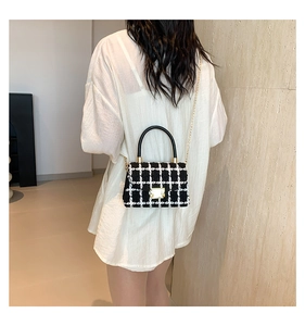 Gros plan du sac en tweed noir et blanc élégant porté à l'épaule par un mannequin