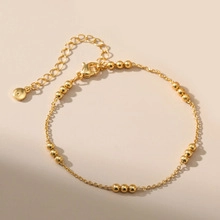 Detailed macro view of minimalist 18K gold-plated beaded chain bracelet with lobster clasp
