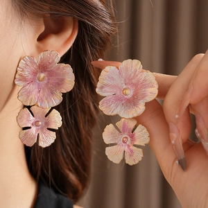 Detail of vintage double-layer enamel flower earrings with pink gradient on female ear