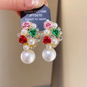 Macro detail of silver 925 earrings featuring crystal roses and a large pearl drop