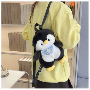 Detail of cute plush penguin backpack with blue plaid bib and adjustable straps on a model