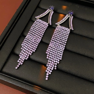 Detail view of purple rhinestone drop earrings with geometric tassels on a black background
