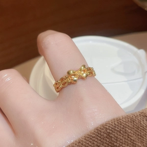 Detailed view of a gold plated bow ring with woven texture on a hand