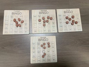 Flat lay view of four wooden sports bingo boards for football basketball soccer and baseball