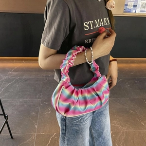 Detail of colorful rainbow pleated shoulder bag showing glossy satin fabric and ruffles