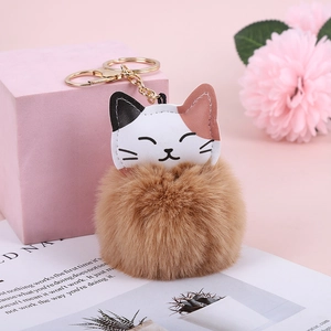 Close-up of a brown faux rabbit fur keychain with a calico cat head and gold metal clip